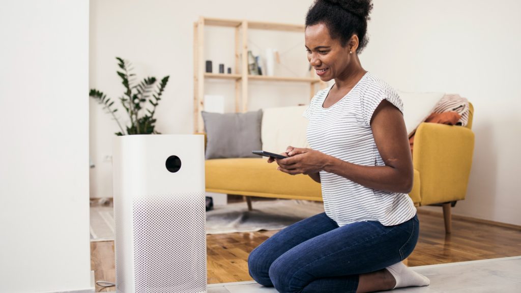 What does air purification do? - woman sitting in front of air purifier in her home