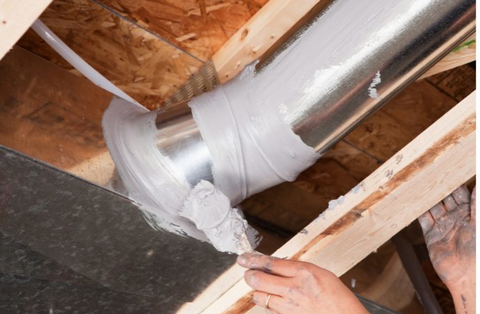 Importance of duct sealing - close up of a contractor sealing an air duct